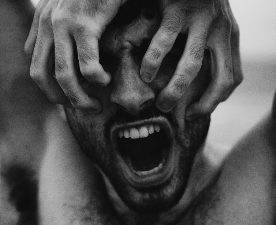 A person with their hands over their face, screaming