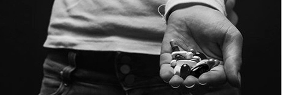 A hand holding a collection of various pills
