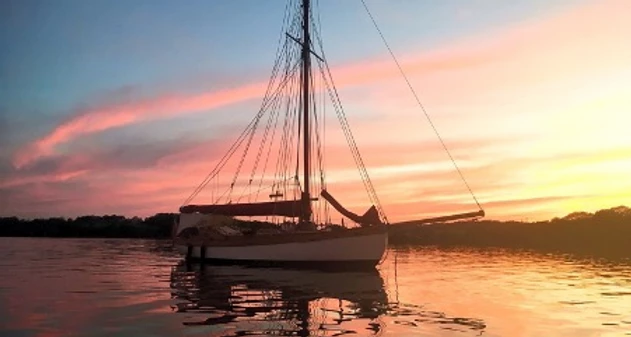 A yacht at anchor on still water at sunset